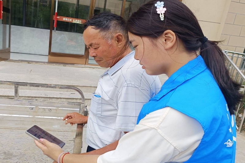 图为实践团成员为老人讲解操作智能手机的方法.jpg