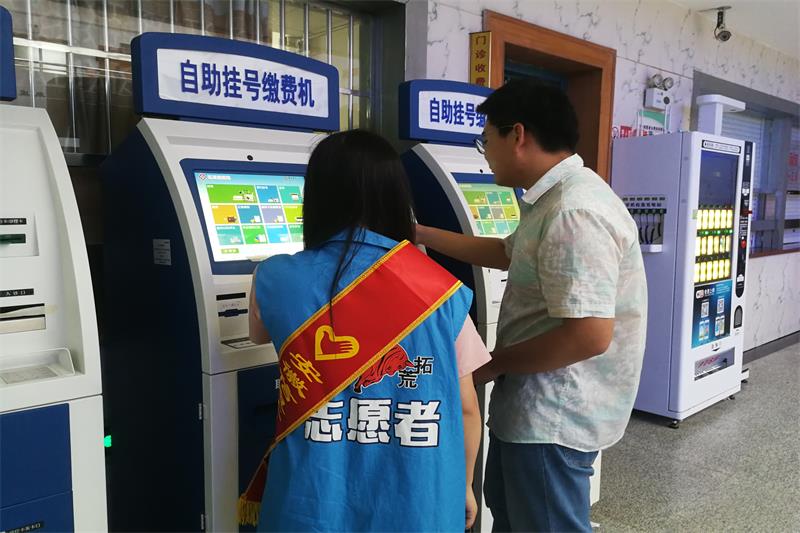 6.志愿者帮助患者使用自动挂号机.JPG