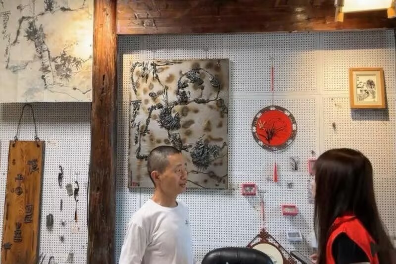 图片三为团队同学采访铁画师傅的画面.png